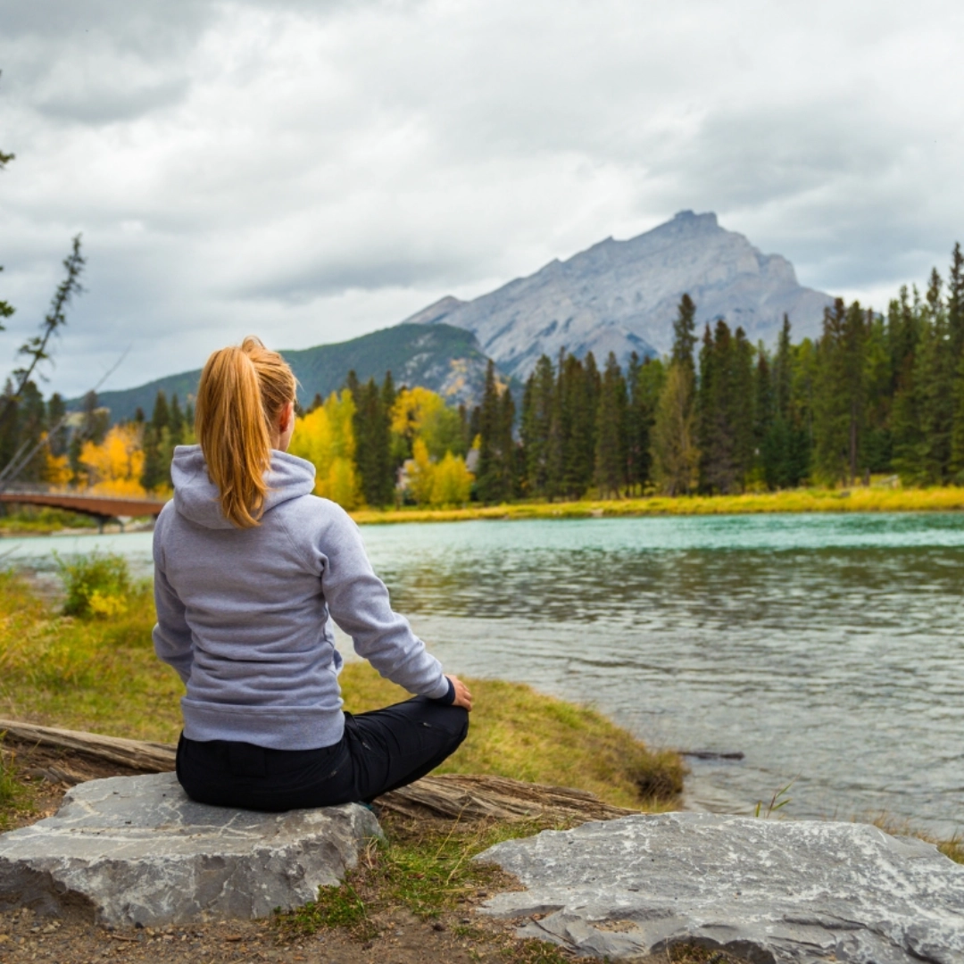 A woman sitting on the side of a river.