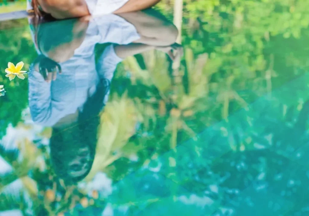 A person sitting on the ground in front of water.