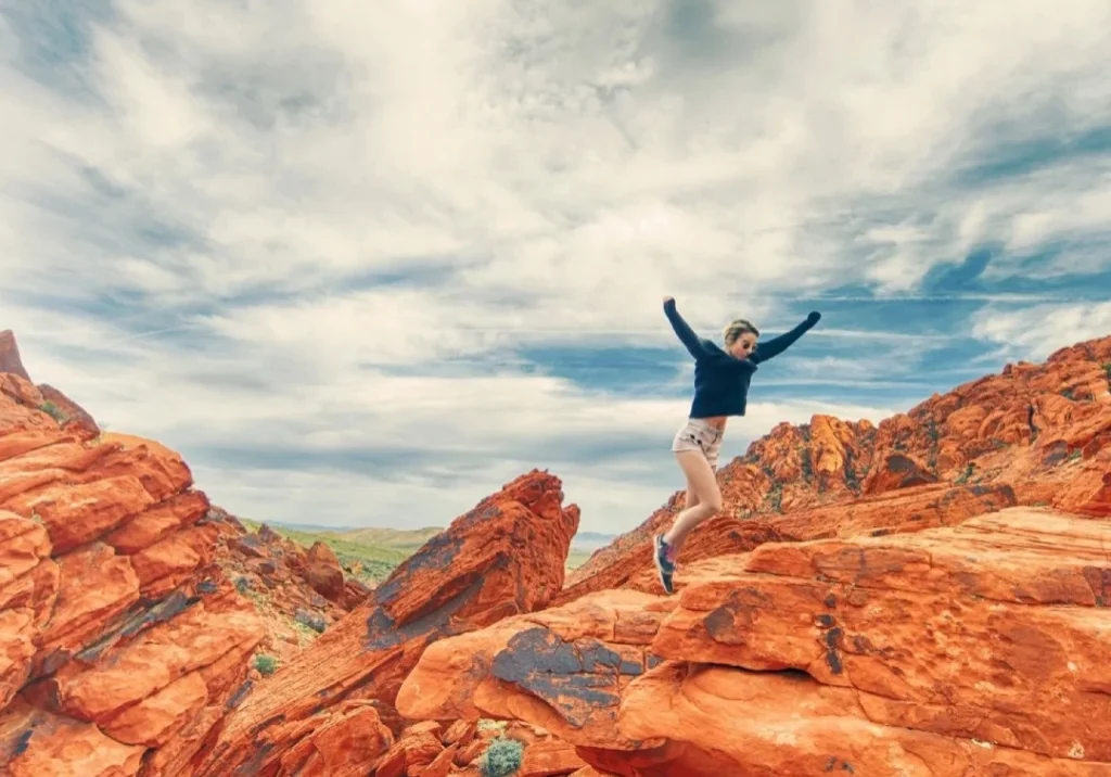 A person standing on top of rocks with arms outstretched.