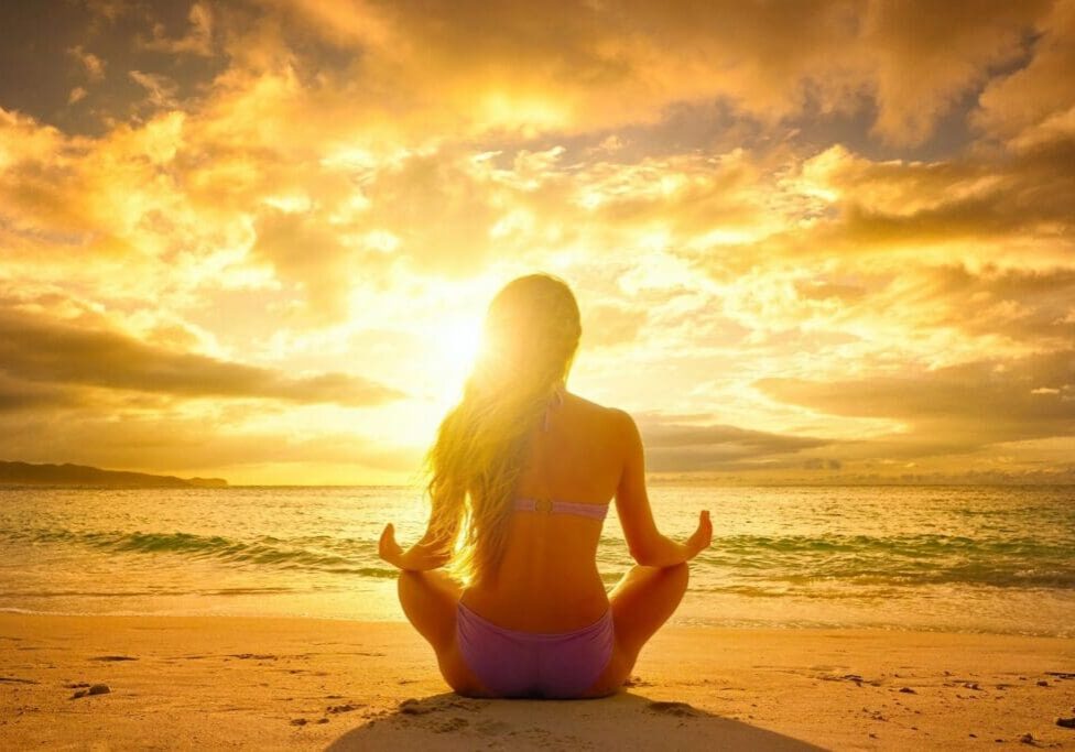 A woman sitting on the beach in front of the ocean.